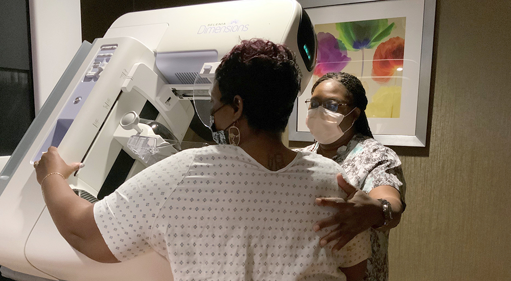 Nurse assisting woman at mammogram screening machine