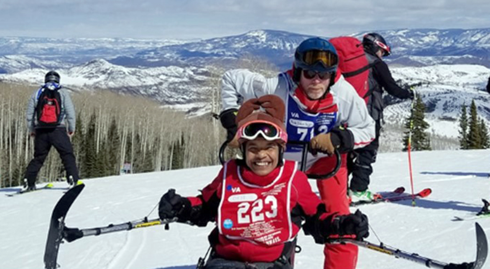 Female Veteran and her adaptive ski instructor prepare for a day on the slopes
