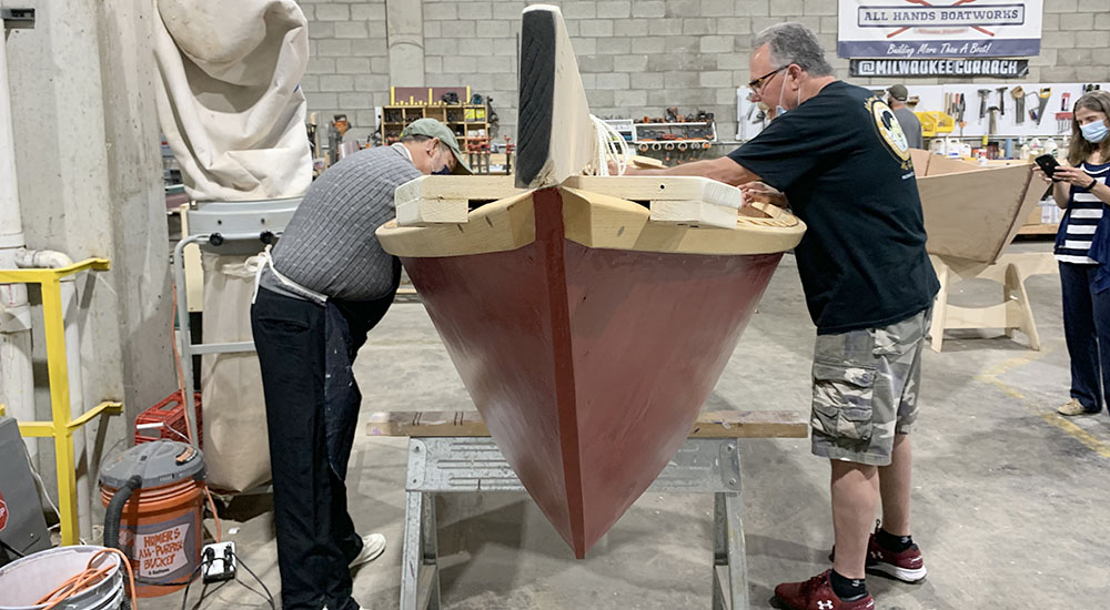 Two men working on the interior of a sailboat
