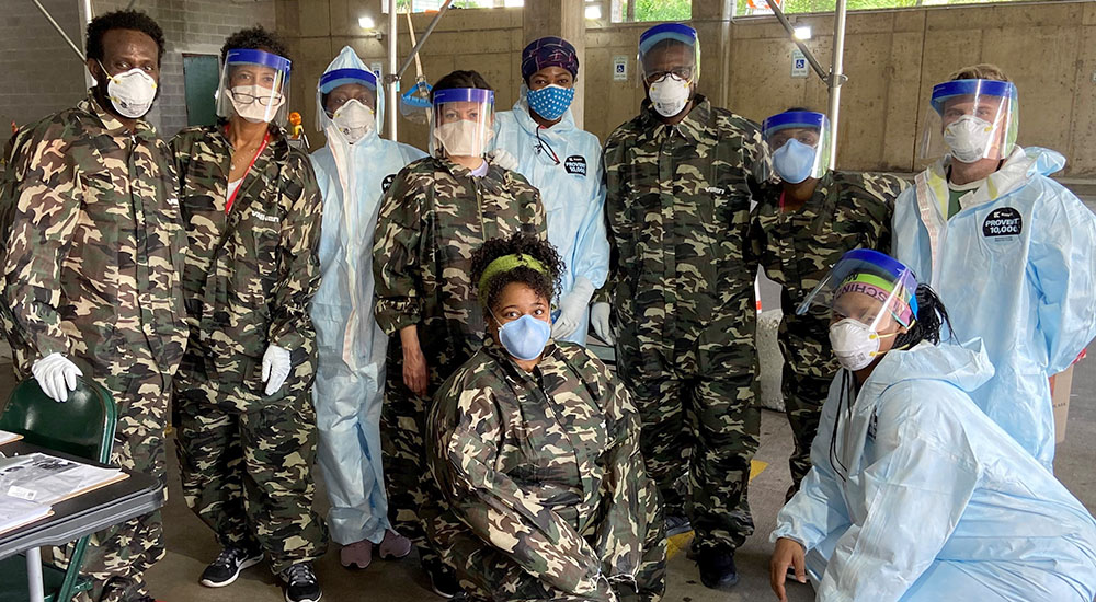 Ten people in fatigues and masks ready to vaccinate