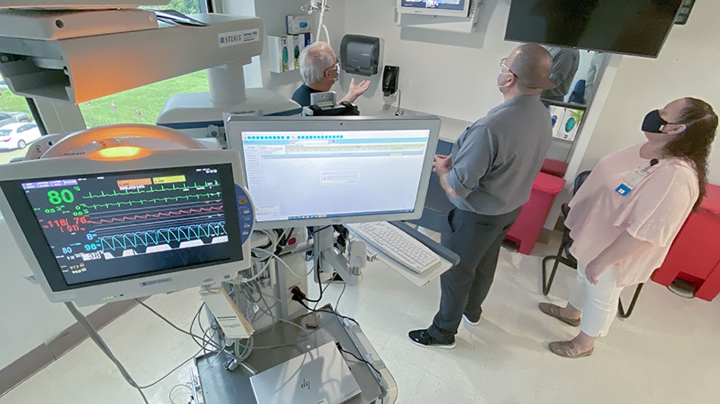 Three clinicians watching an ICU monitor