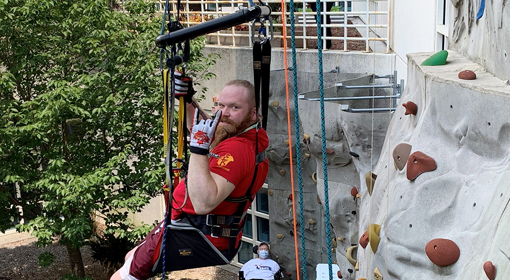 Man in harness beside rock climbing wall