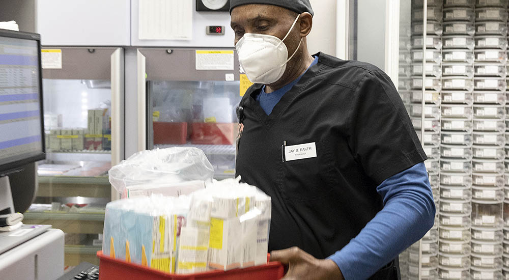 Man carrying tray full of prescription medications