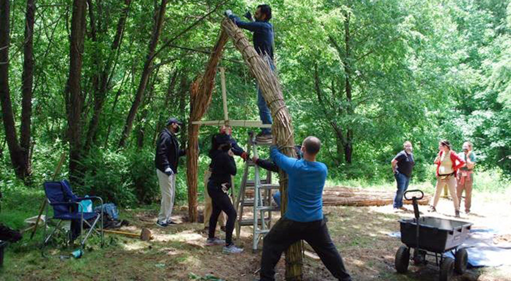 Several people work together to tie reeds for a structure that will be a place of healing