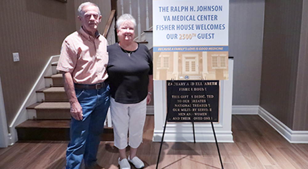 Veteran and wife next to poster welcoming 2500th Veteran