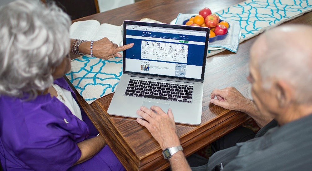 A man and a woman looking at the My HealtheVet homepage on a laptop.