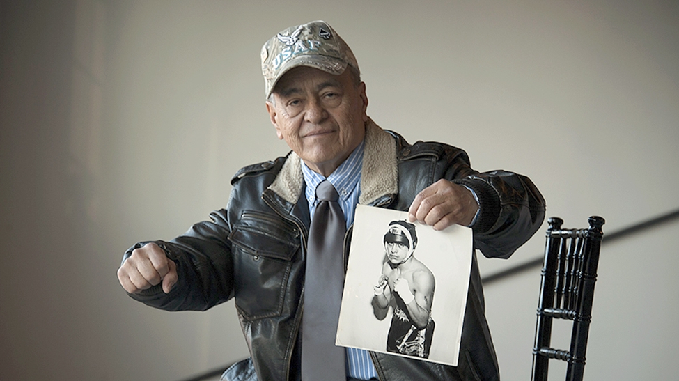 Man holding a photo of himself younger and in boxing gear