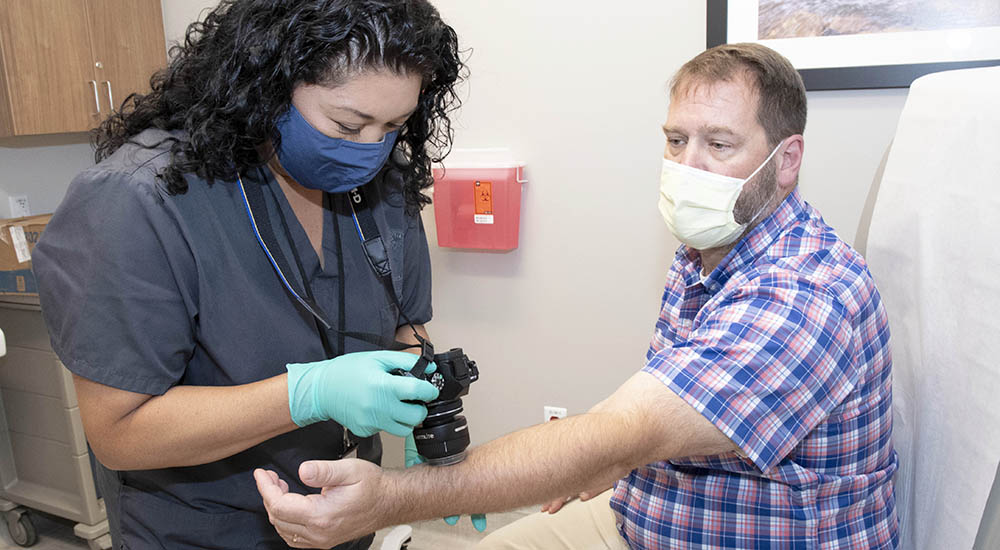 Outpatient clinic technician takes dermatology images of Veteran’s arm
