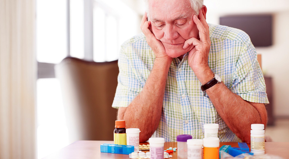 Senior man sitting and looking at his prescriptions medication from a community providers