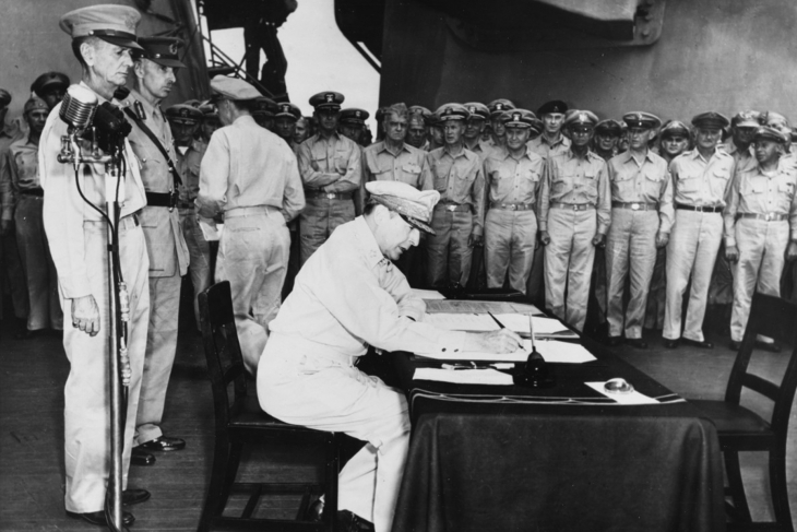 Army Gen. Douglas MacArthur signs the Instrument of Peace as the supreme allied commander during formal Japanese surrender ceremonies on the USS Missouri in Tokyo Bay, Sept. 2, 1945. Standing behind MacArthur are Army Lt. Gen. Jonathan Wainwright, left; and British Lt. Gen. A. E. Percival, commander of Singapore.