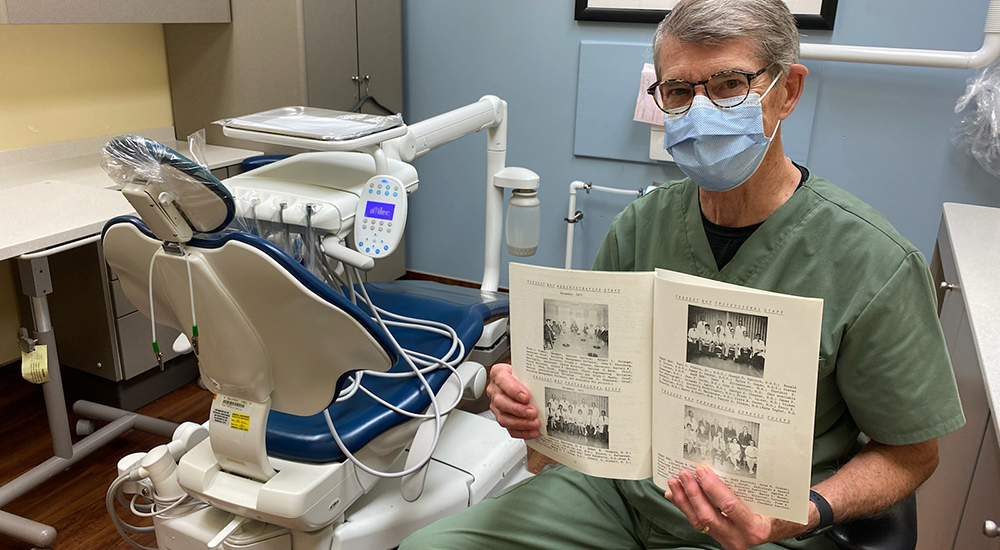 Dentist in dental operatory holding up scrapbook