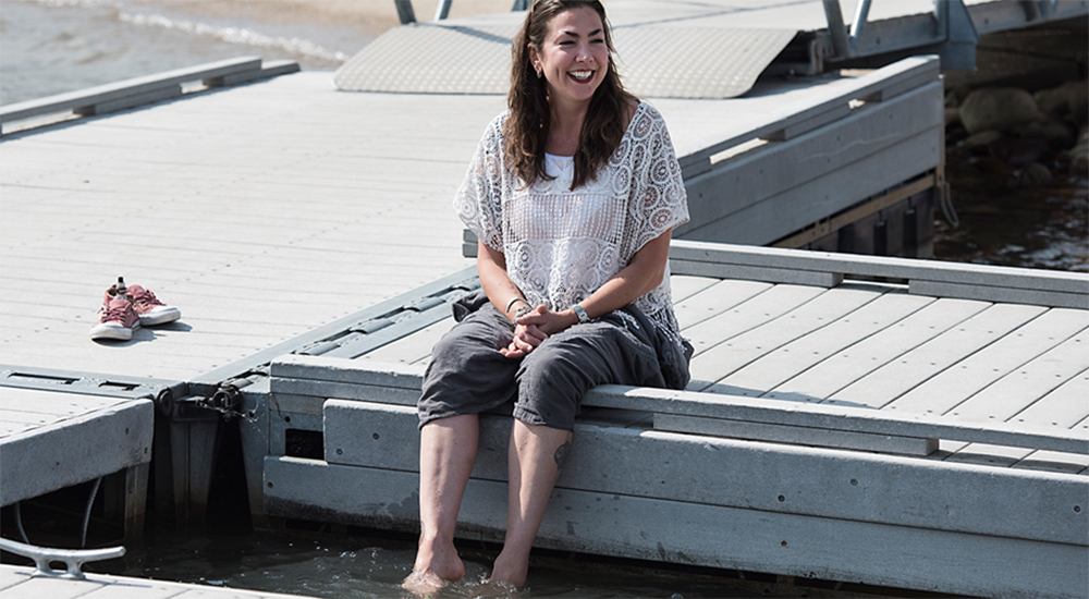 Smiling woman sitting on dock, practicing mindfulness