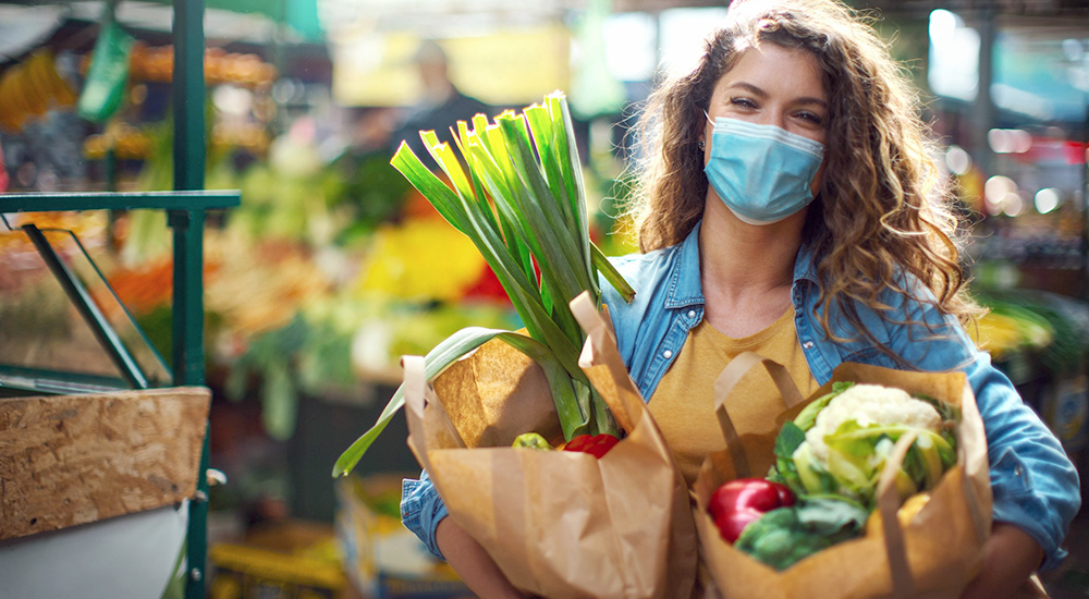 Lady with two paper bags of produce at a farmers market