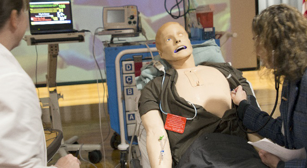 Two nurses practice procedures on manikin patient at the simulation center