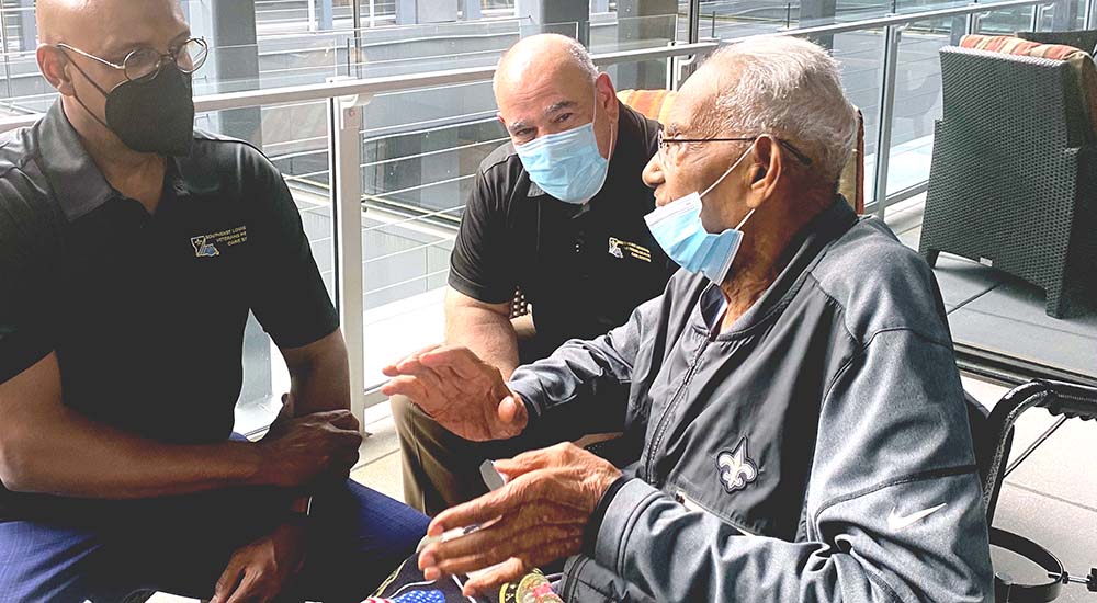 Veteran on his 112th birthday, talking with two VA executives