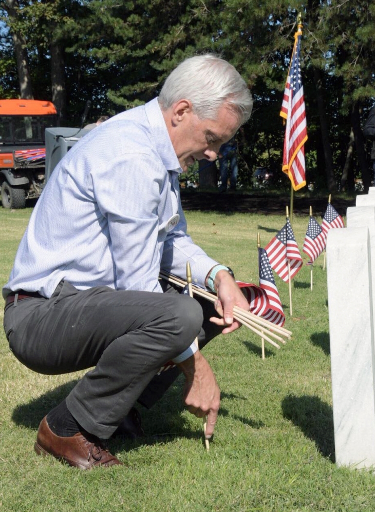 VA Secretary Denis McDonough plants a flag on a Veteran's grave at Quantico National Cemetery in Virginia Sept. 10, 2021.