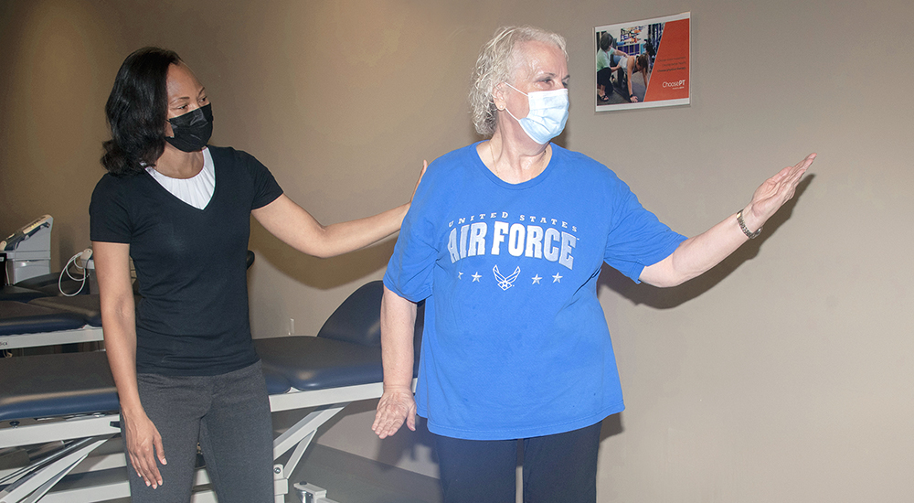 Physical therapist assisting older Veteran in therapy session