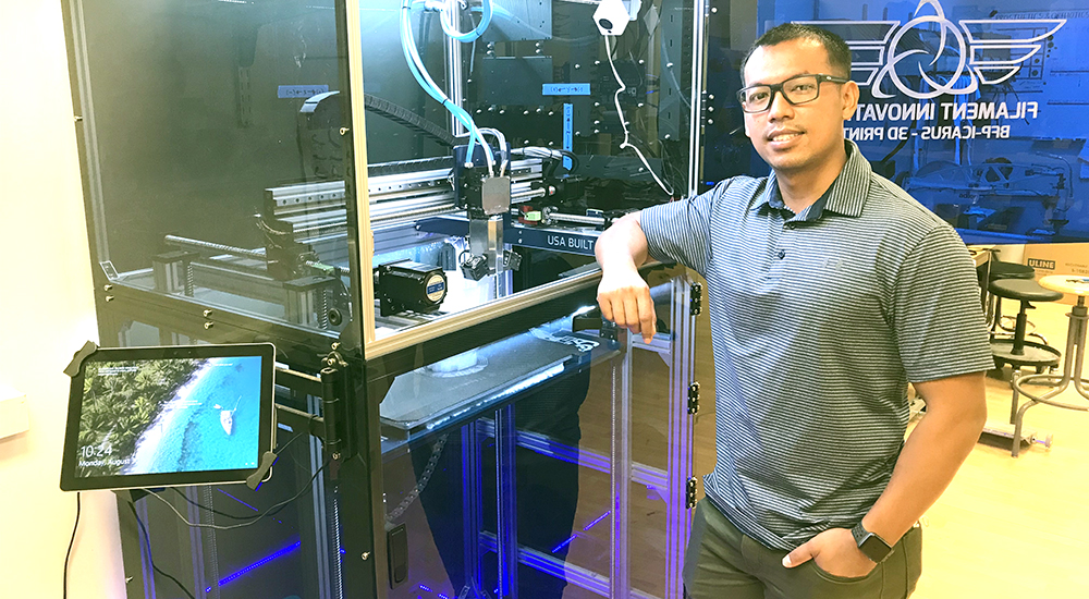 Man standing next to large 3D printer used to create prosthetics
