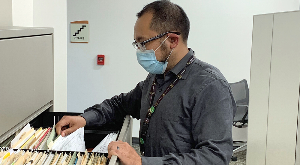 Man wearing mask filing document