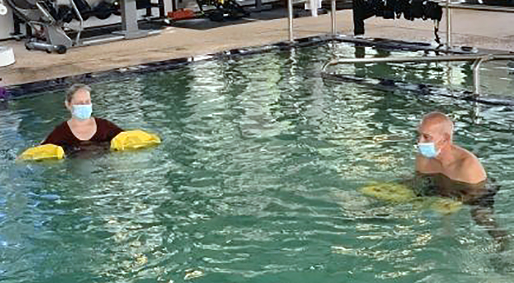 Man and woman with floats in aquatic therapy pool