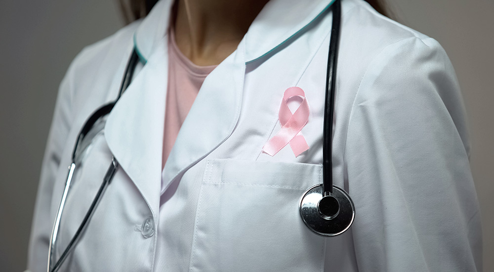 Pink ribbon symbolizing breast cancer awareness on doctor's coat