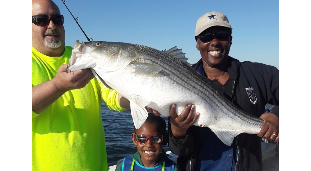 Woman, her son, and a man hold a large fish