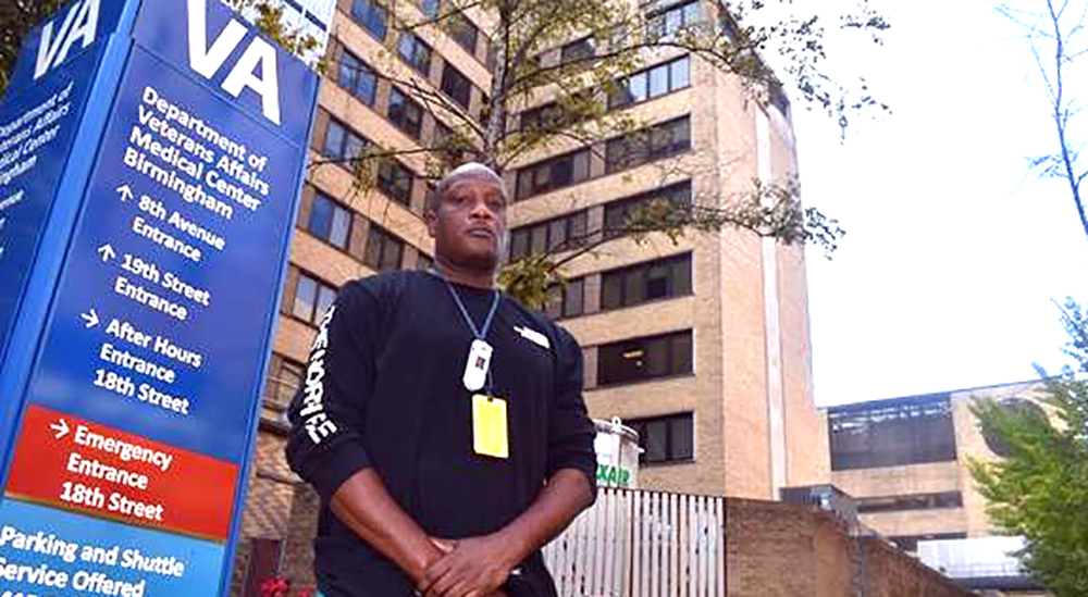 VA patient escort in front of medical center sign