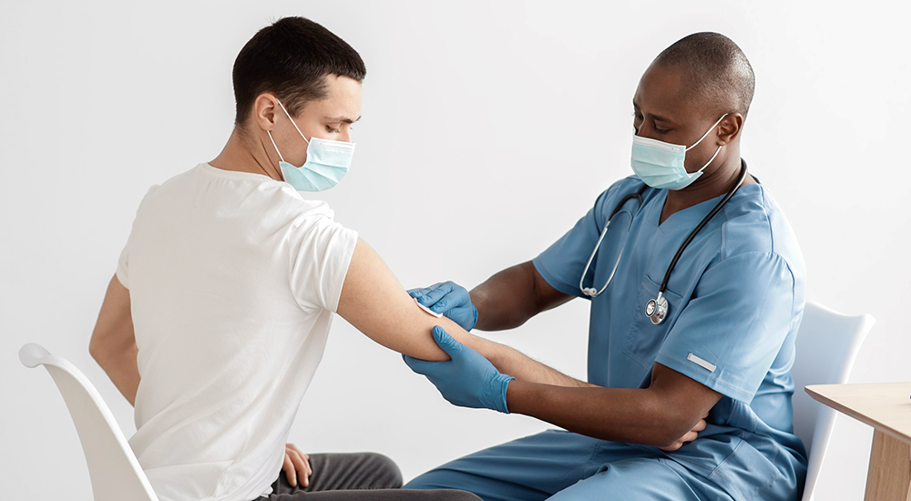 Nurse prepares male patient for shot during flu season