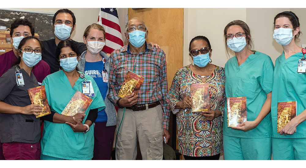 Hospital staff and patient and his wife pose for photo during his thank you visit