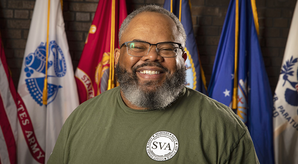 Smiling Veteran in front of flags