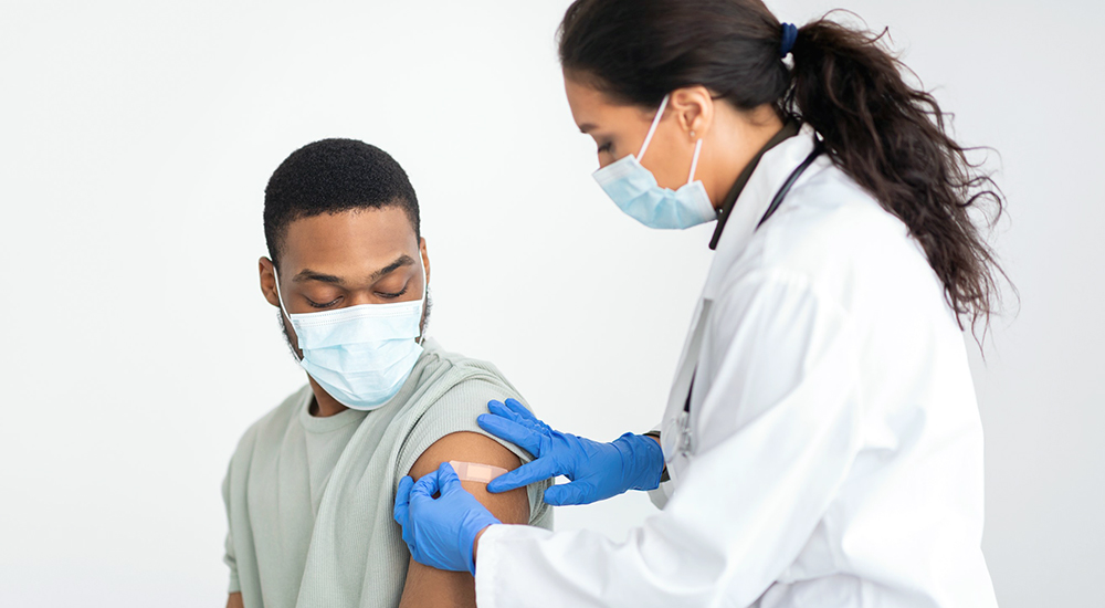 Nurse applying bandage to Veteran's arm after flu shot