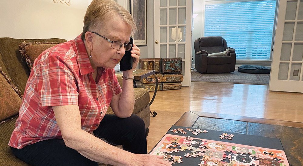 Senior woman practices cognitive training by talking on the phone while doing a jigsaw puzzle