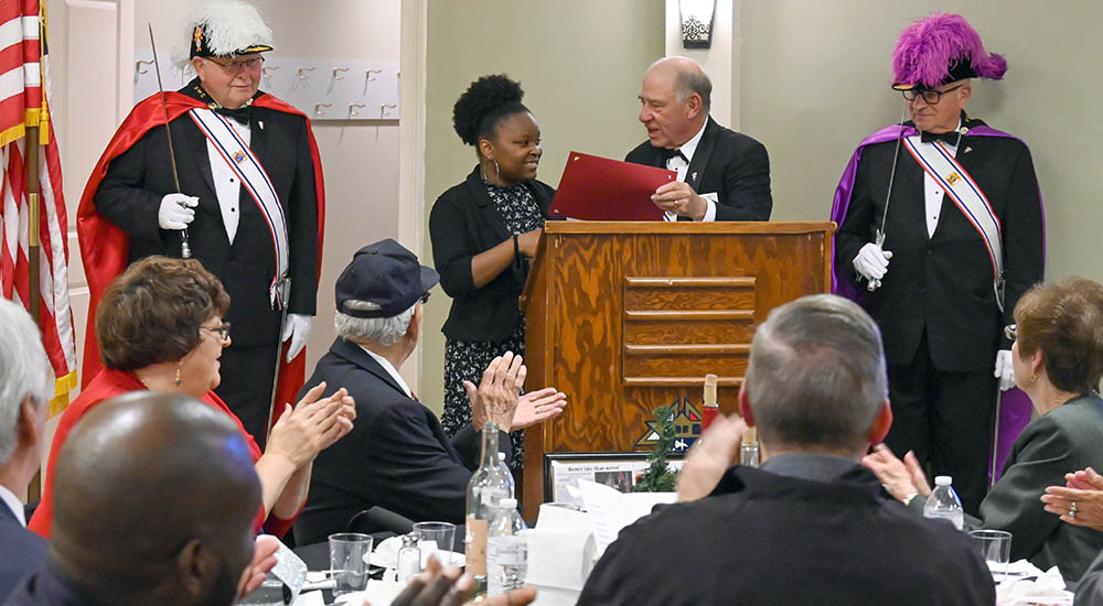 Knights of Columbus audience applauds young woman receiving award
