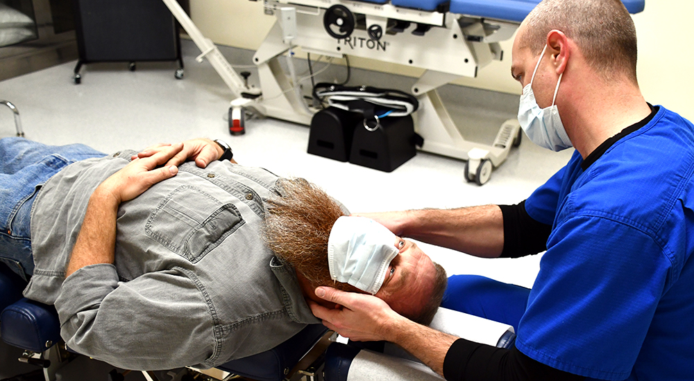 Chiropractor adjusts neck of Veteran patient