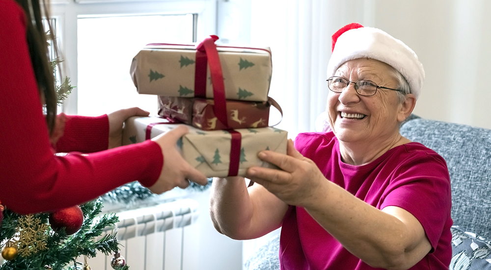 Elderly woman wearing Santa hat receiving gifts