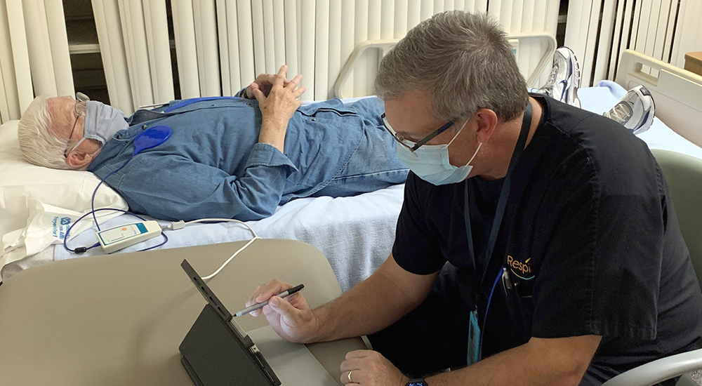 Patient in bed as doctor adjusts sleep apnea device