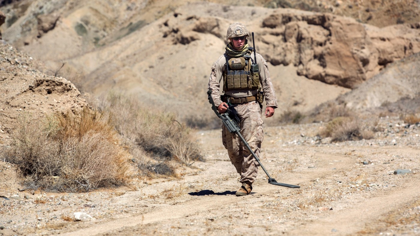 An explosive ordnance disposal technician performs a sweep with a metal detector during a post-blast analysis at a Marine training site in California. Blast exposure is common among service members, but its chronic psychiatric effects are not well-understood.