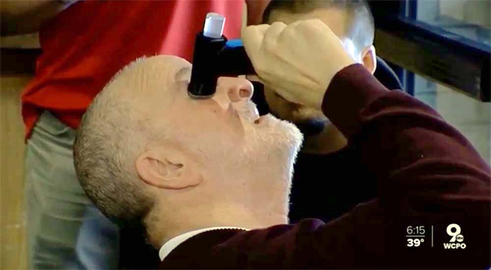 Man using device to put eyedrops in his eye