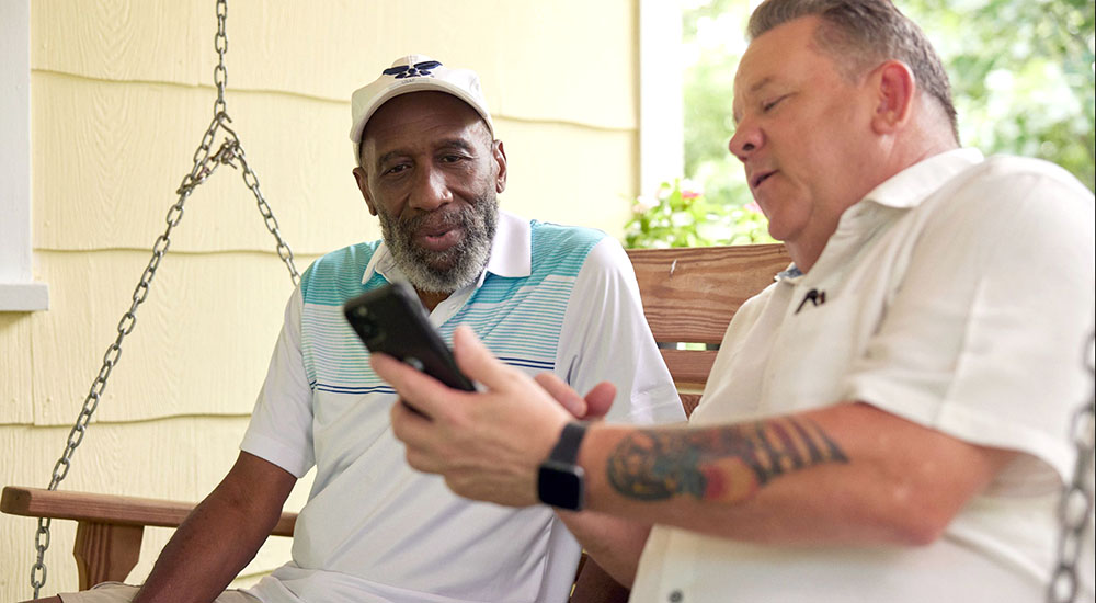 Man showing features of drinking prevention program on phone to Veteran
