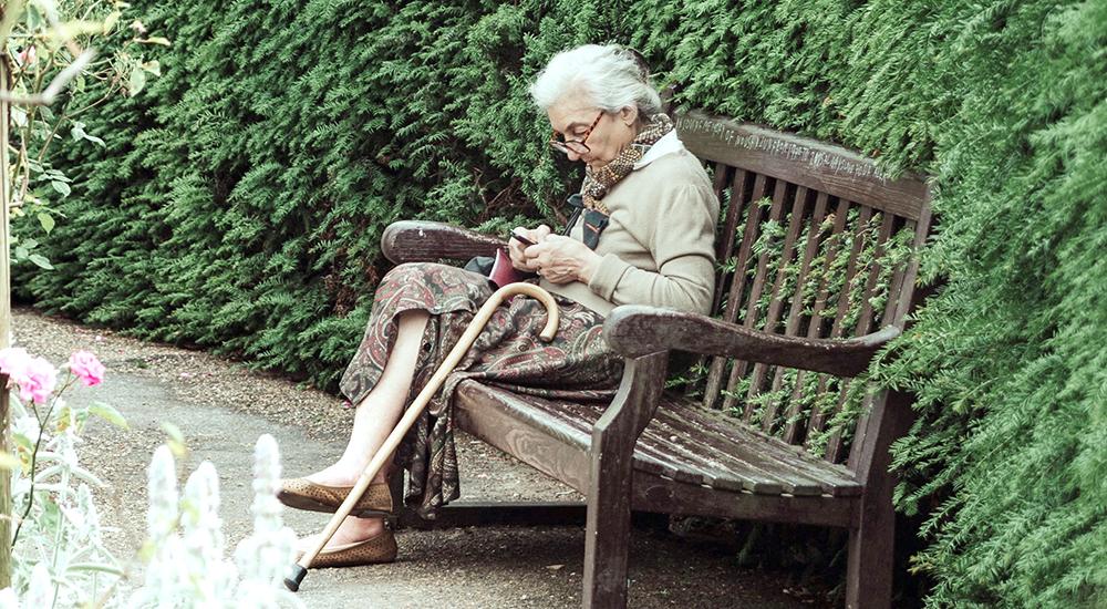 Senior woman on a bench texting