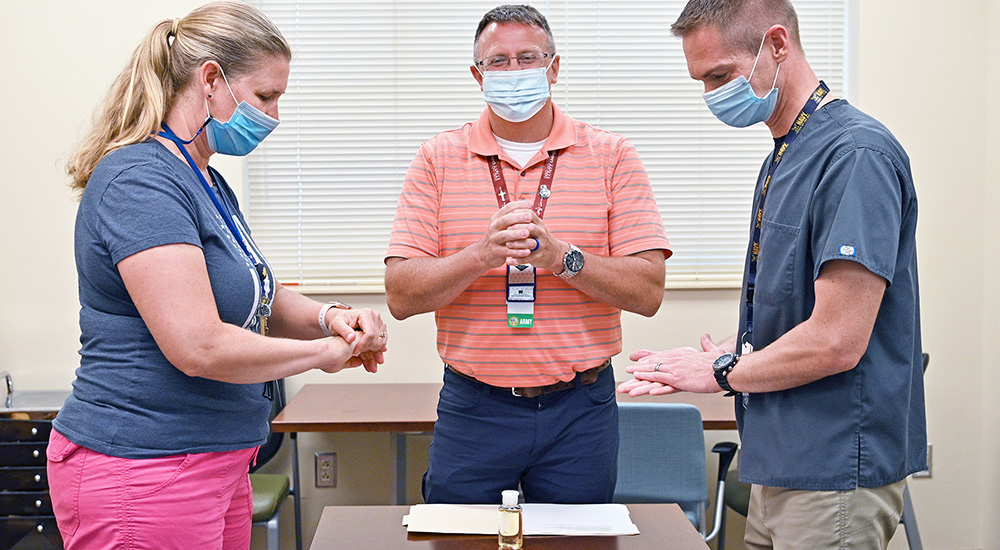 Chaplain and two nurses conduct Blessing of the Hands ceremony during Nurses Week