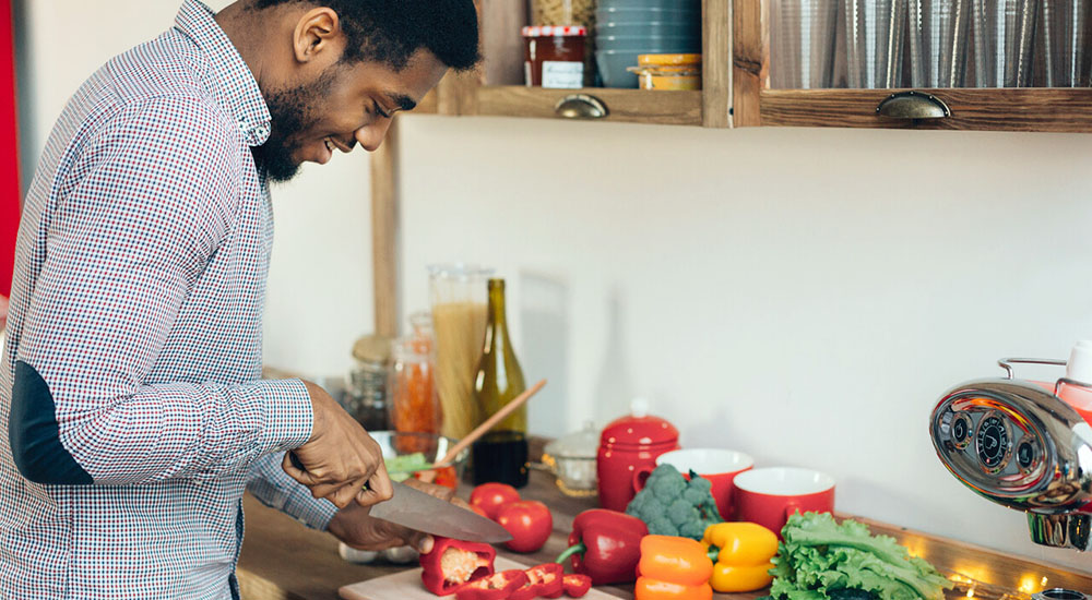 Man in kitchen chopping red peppers, nutrition