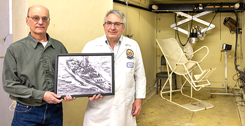 Two men with photo of WWII battleship
