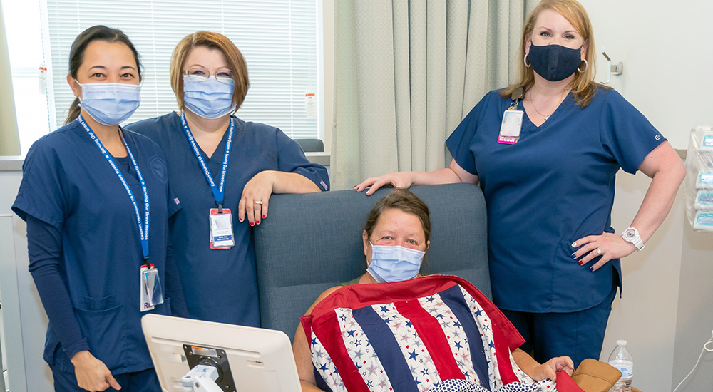 Three nurses with chemotherapy patient and quilts