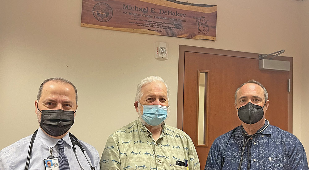 Veteran and two doctors in front of sign on the wall