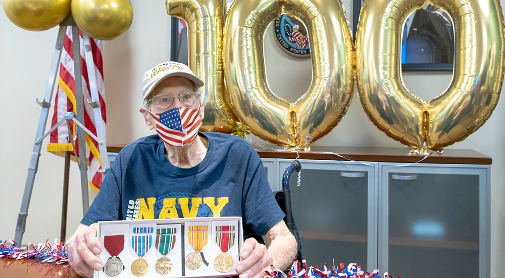 Veteran holding medals celebrates his 100th birthday