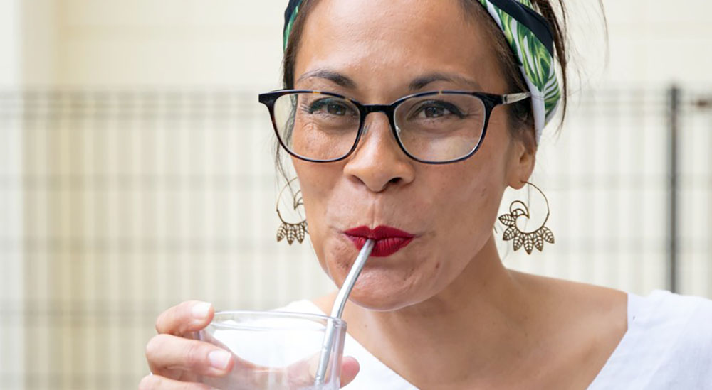 Smiling woman in menopause drinking through a straw