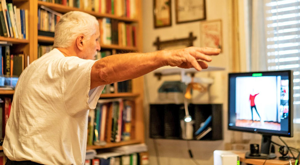 Senior Veteran following TeleRehabilitation exercises on computer monitor