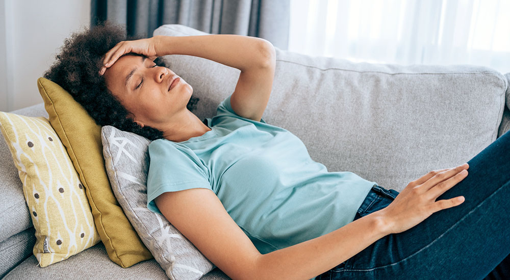 Woman sick with long COVID lying on sofa