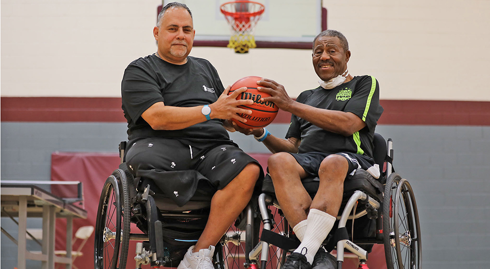 Two Veterans, basketball rivals, in wheelchairs holding basketball
